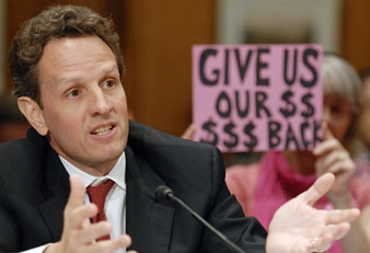 A protester holds a sign behind Geithner as he addresses a hearing of the Congressional Oversight Panel of the TARP. Reuters Photos<br/> 